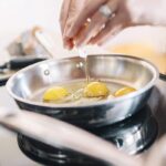 Eggs being cooked in steel frying pan.