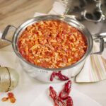 Topview of tomato and lobster dish being cooked in large steel stock pot.