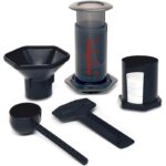 Aeropress with various accessories like coffee scoop, filters, funnel and stirrer.