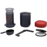 Aeropress Go with various accessories like coffee scoop, filters box and cup with lid.