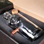 Glass decanter with embedded bullet in carton and foam packaging.