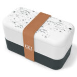 Rectangular lunchbox with white upper half, soft black lower half, subtle shooting star designs on the lid and gold-colored elastic band.