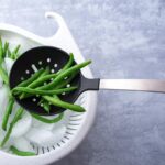 Close up of skimmer holding cooked green beans.