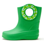 Side view of green children's rain boot with sticker around the carrying hole showing green monster eyes