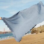 Blue baby blanket being thrown open on the beach