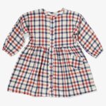 White longsleeve kids' dress with blue and red lines running horizontal and vertical, buttons down the front and a small pocket.