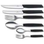 Set of steak knife, table knife, fork, spoon, teaspoon and cake fork. All with black plastic handles.