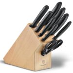 Wooden knife block including 7 knives, a sharpening rod and a pair of scissors, all with black plastic handles.