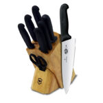 Wooden knife block including 5 knives, a sharpening rod and a pair of scissors, all with black plastic handles.