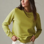 Woman wearing long sleeve, green crew sweatshirt.