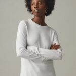 Woman wearing white, long sleeve, crew neck t-shirt.