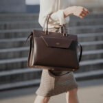 Woman carrying brown leather handbag on arm.