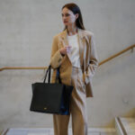 Woman carrying black leather bag on arm.