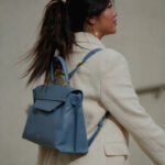 Woman carrying blue leather handbag as backpack.