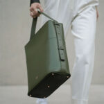 Large dark green square leather bag with strap.