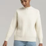 Young woman wearing creme colored woolen sweater.