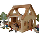 Wooden dollhouse farm with animal figurines.