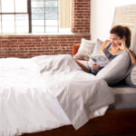 Woman reading in bed under a warm duvet.