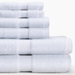 Pile of folded white cotton towels in three different sizes.