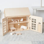 Wooden dollhouse with opened panels and two floors filled with dollhouse furniture.