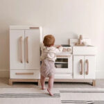 Toddler playing wooden toy kitchen.